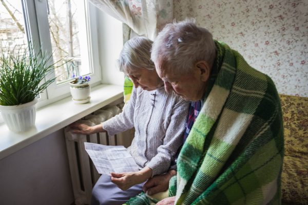 The,Senior,Woman,Holding,Gas,Bill,In,Front,Of,Heating